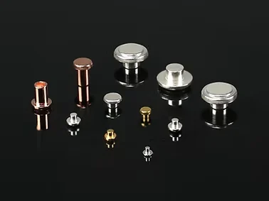 Metal electrical contact rivets and contact buttons of different sizes on a black background.
